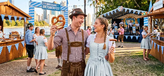 Couple in traditional Dirndl and Lederhosen celebrating Oktoberfest Brisbane with German food and live music.