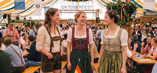 Dirndl alternatives for Oktoberfest showcasing women's lederhosen, traditional dirndl dresses, and Bavarian festival outfits inside a festive beer tent.