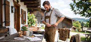 Man trying on classic Bavarian Lederhosen to find the perfect size and comfortable fit.