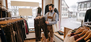 Customer shopping for authentic lederhosen during the off-season in a traditional German clothing store with a wide selection of Bavarian outfits.