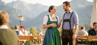 Man in lederhosen and woman in a dirndl showcasing authentic Tracht fashion at an outdoor festival